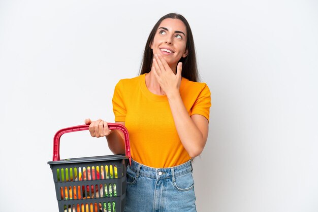 Young caucasian woman holding a shopping basket full of food