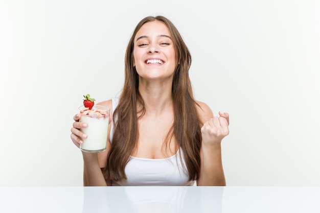 Young caucasian woman holding a smoothie cheering carefree and excited. Victory concept.