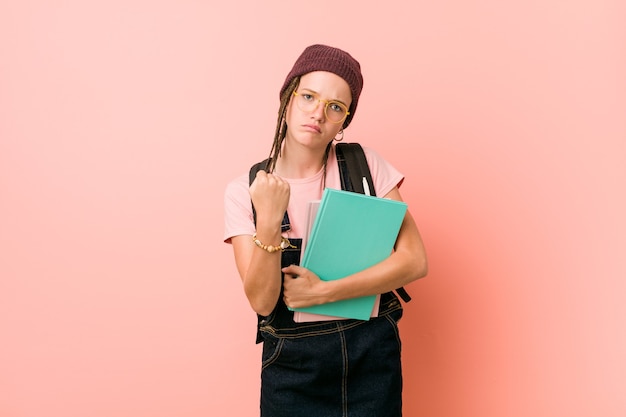 Young caucasian woman holding some notebooks showing fist to camera, aggressive facial expression.