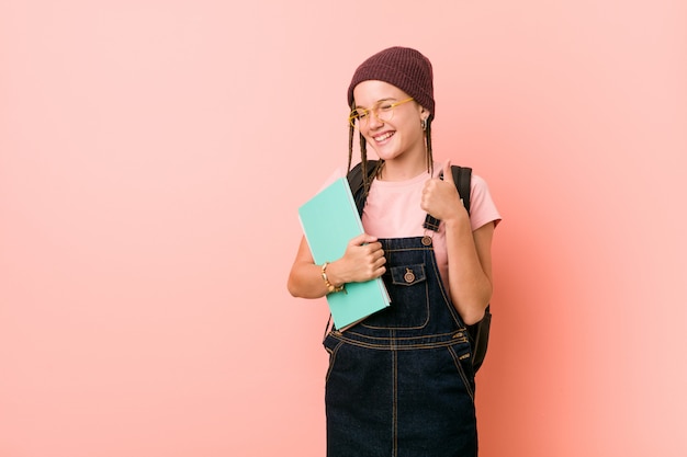 Young caucasian woman holding some notebooks smiling and raising thumb up