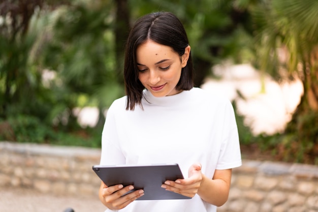 屋外でタブレットを保持している若い白人女性