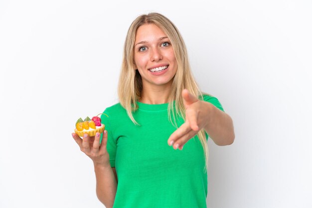 Young caucasian woman holding a tartlet isolated on white background shaking hands for closing a good deal