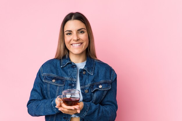 Young caucasian woman holding a tea cup smiling confident with crossed arms.