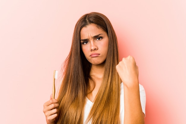 Young caucasian woman holding a toothbrush showing fist to camera