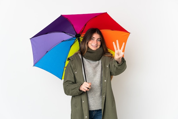 Молодая кавказская женщина, держащая зонтик, изолированная на белом, счастлива и считает три пальцами