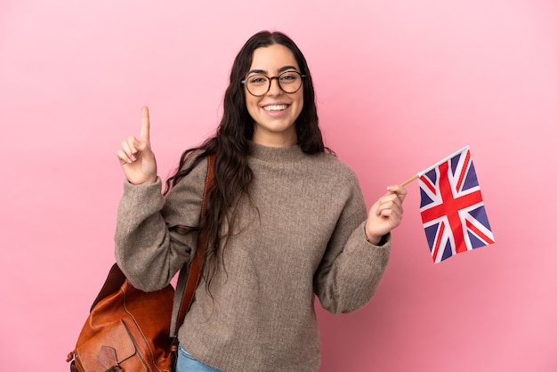 Young caucasian woman holding an United Kingdom flag isolated on pink background pointing up a great idea