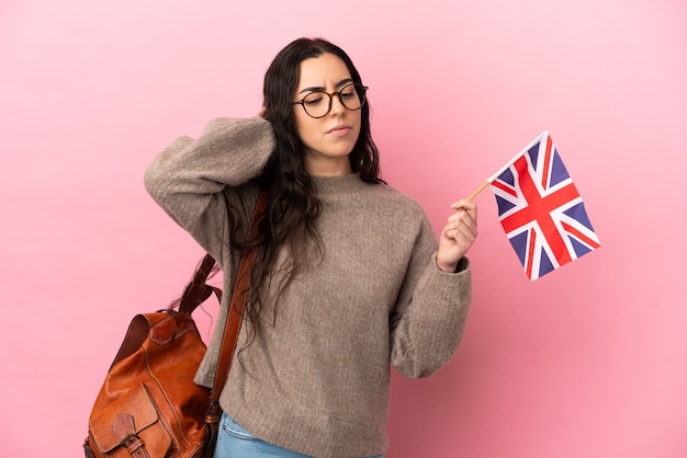 Young caucasian woman holding an United Kingdom flag isolated on pink wall having doubts