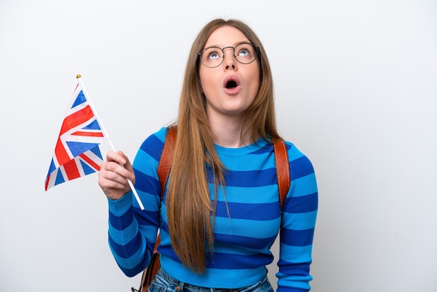 Young caucasian woman holding an United Kingdom flag isolated on white background looking up and with surprised expression