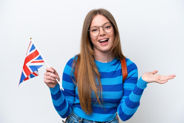 Young caucasian woman holding an United Kingdom flag isolated on white background with shocked facial expression