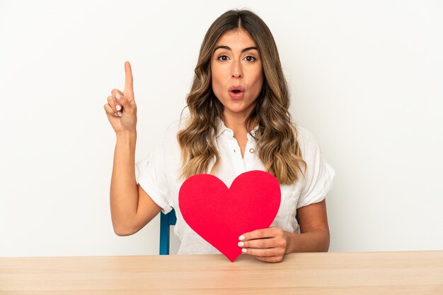 Young caucasian woman holding a valentines day heart isolated having some great idea, concept of creativity.