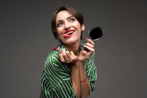 A young caucasian woman holds makeup brushes isolated on grey background