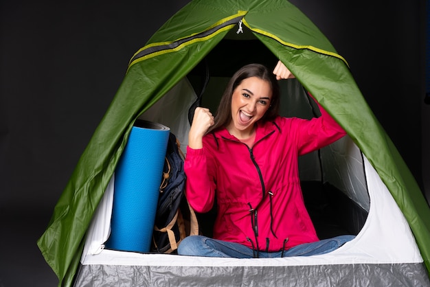 사진 승리를 축하 캠핑 녹색 텐트 안에 젊은 백인 여자
