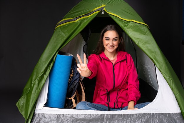 Young caucasian woman inside a camping green tent