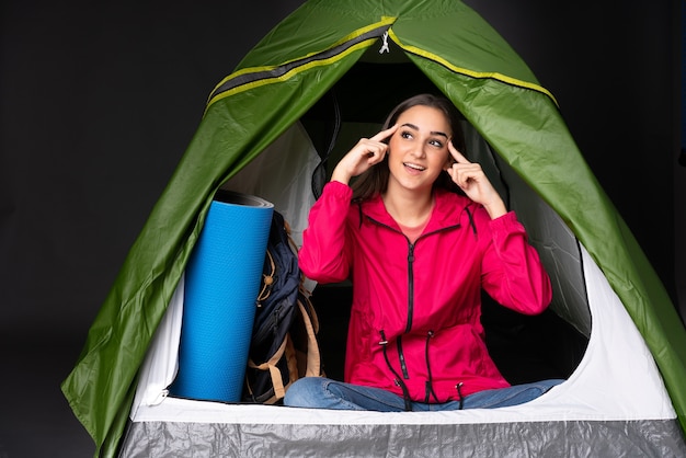 Young caucasian woman inside a camping green tent