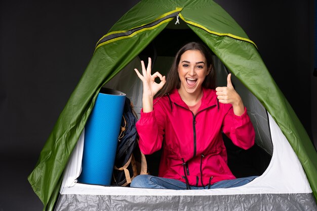 Young caucasian woman inside a camping green tent