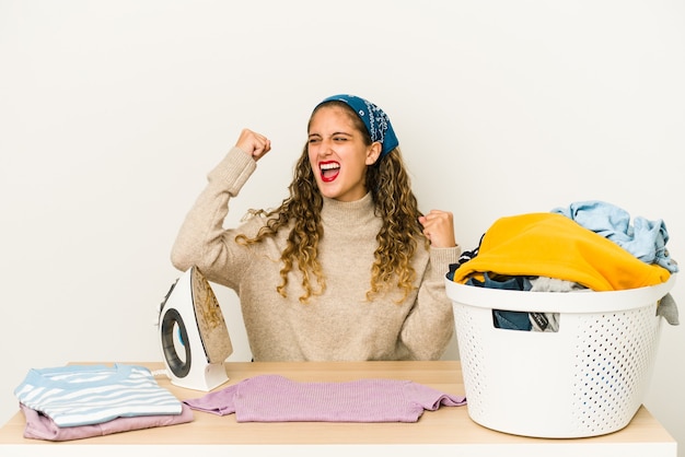 Young caucasian woman ironing clothes isolated