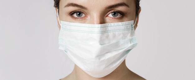 젊은 백인 여자는 바이러스로부터 보호하기 위해 얼굴 마스크를 쓰고있다