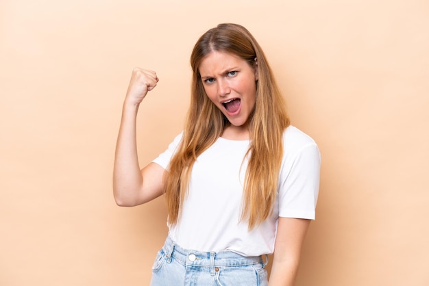 Young caucasian woman isolated on beige background celebrating a victory