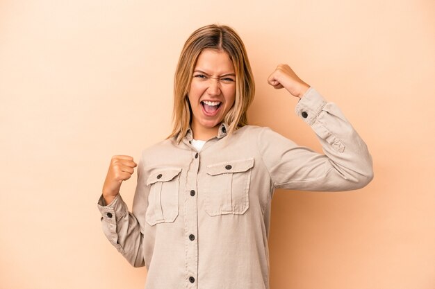 Young caucasian woman isolated on beige background cheering carefree and excited. Victory concept.