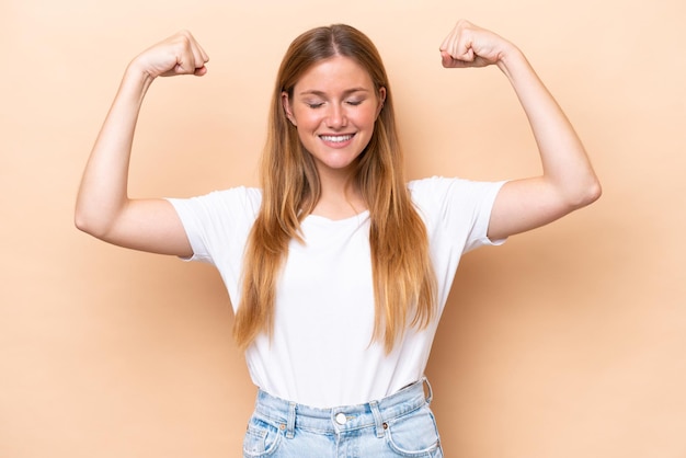 Young caucasian woman isolated on beige background doing strong gesture