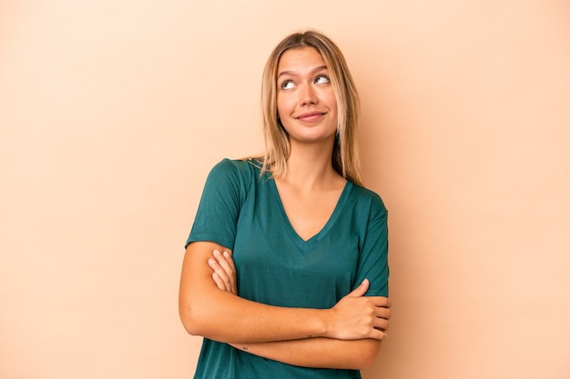 Young caucasian woman isolated on beige background dreaming of achieving goals and purposes