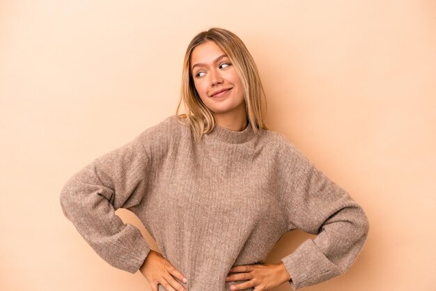 Young caucasian woman isolated on beige background dreaming of achieving goals and purposes