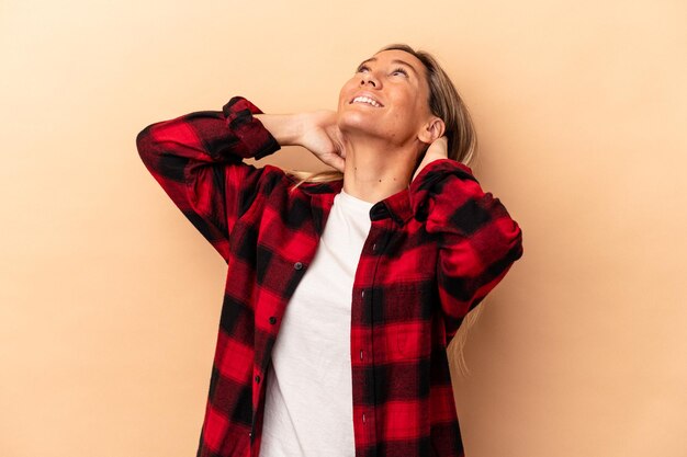 Young caucasian woman isolated on beige background feeling confident, with hands behind the head.