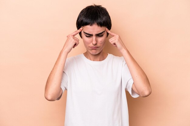 Photo young caucasian woman isolated on beige background focused on a task, keeping forefingers pointing head.