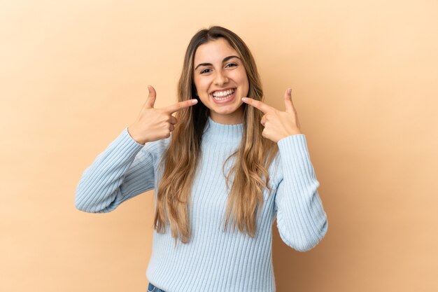 Young caucasian woman isolated on beige background giving a thumbs up gesture