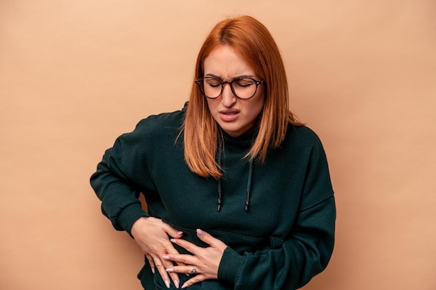 Foto giovane donna caucasica isolata su sfondo beige con dolore al fegato, mal di stomaco.