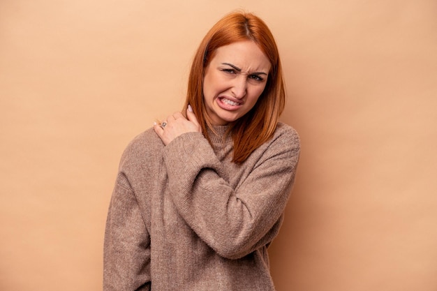 Young caucasian woman isolated on beige background having a shoulder pain