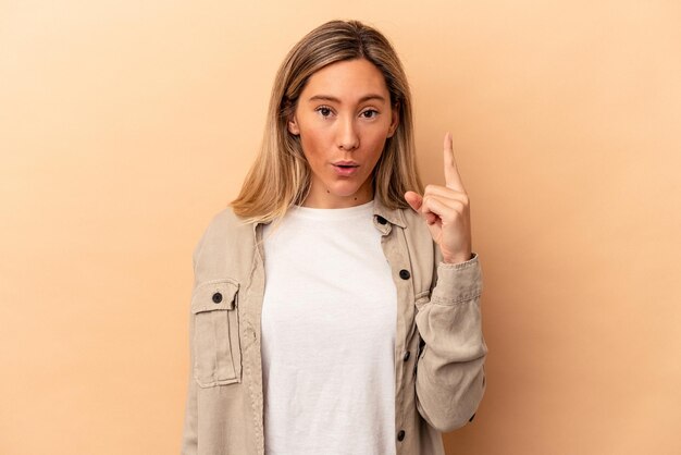 Young caucasian woman isolated on beige background having some great idea, concept of creativity.