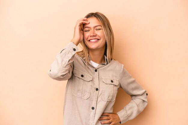 Young caucasian woman isolated on beige background joyful laughing a lot. Happiness concept.