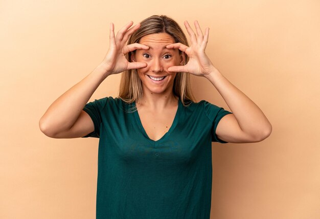 Young caucasian woman isolated on beige background keeping eyes opened to find a success opportunity.