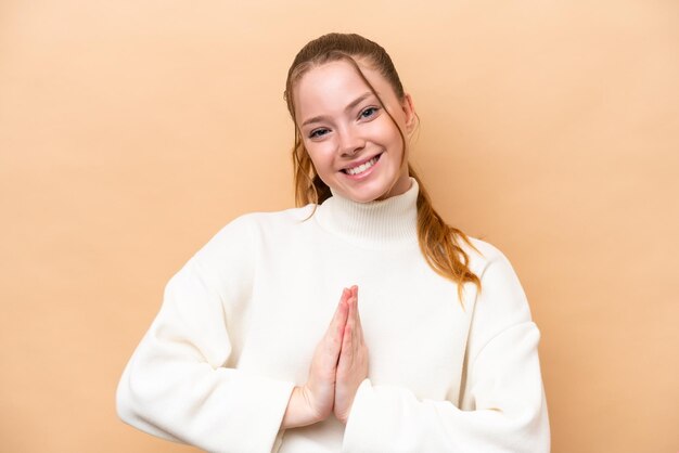 Young caucasian woman isolated on beige background keeps palm together Person asks for something