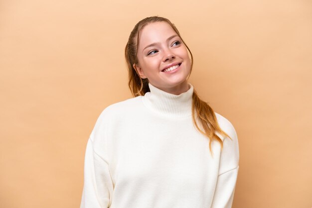 Young caucasian woman isolated on beige background laughing