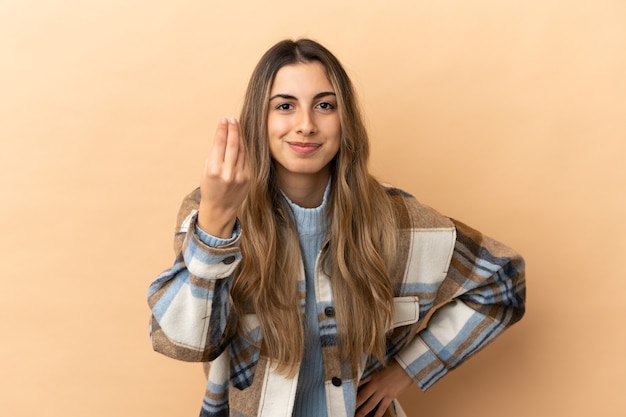 Foto giovane donna caucasica isolata su fondo beige che fa gesto italiano