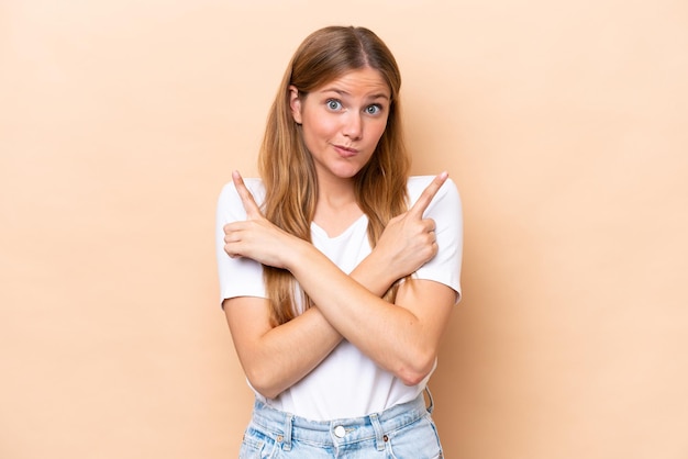 Young caucasian woman isolated on beige background pointing to the laterals having doubts