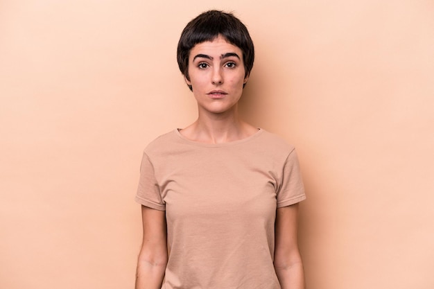 Young caucasian woman isolated on beige background sad, serious face, feeling miserable and displeased.