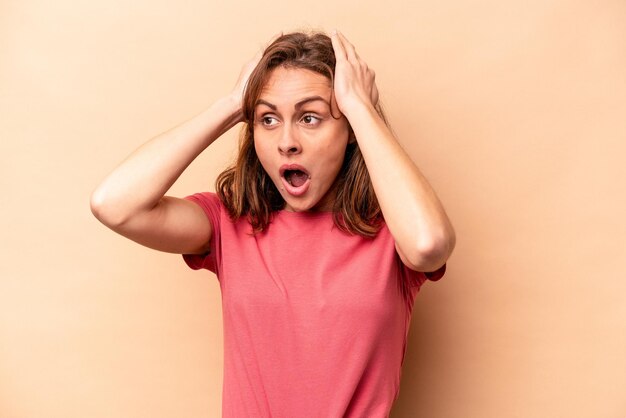 Photo young caucasian woman isolated on beige background screaming very excited passionate satisfied with something