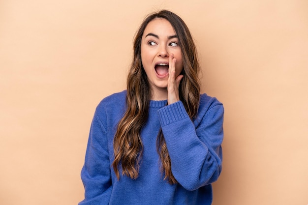 Young caucasian woman isolated on beige background shouting excited to front