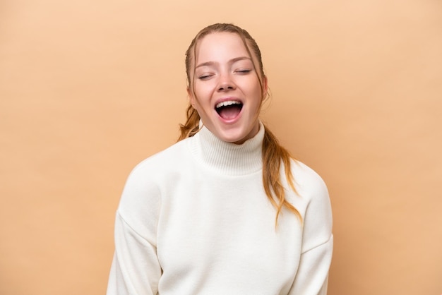 Young caucasian woman isolated on beige background shouting to the front with mouth wide open