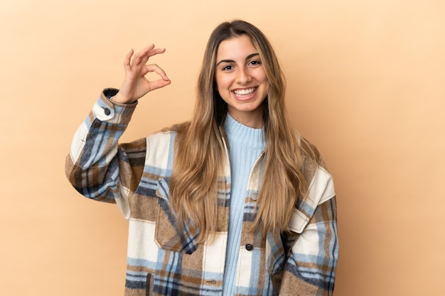 Young caucasian woman isolated on beige background showing ok sign with fingers