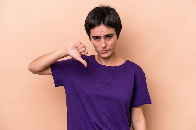 Young caucasian woman isolated on beige background showing thumb down, disappointment concept.