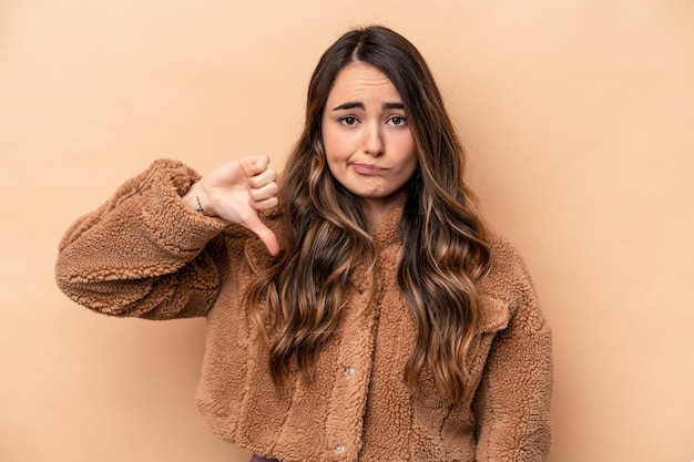 Young caucasian woman isolated on beige background showing thumb down disappointment concept