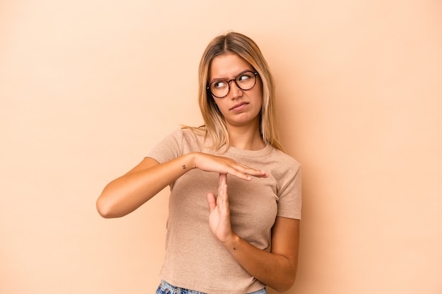 Young caucasian woman isolated on beige background showing a timeout gesture.