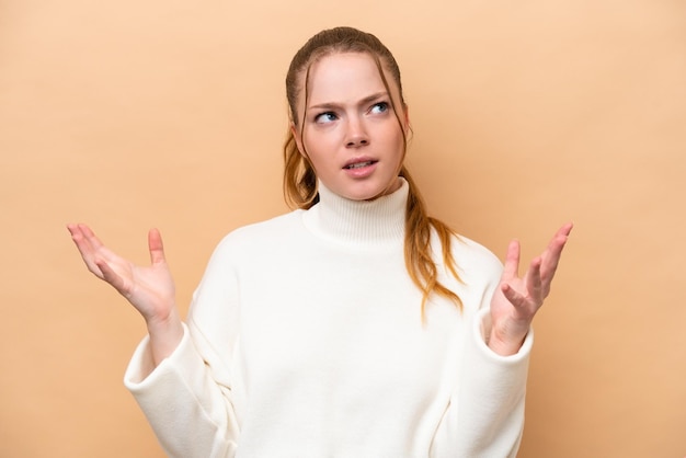 Young caucasian woman isolated on beige background stressed overwhelmed