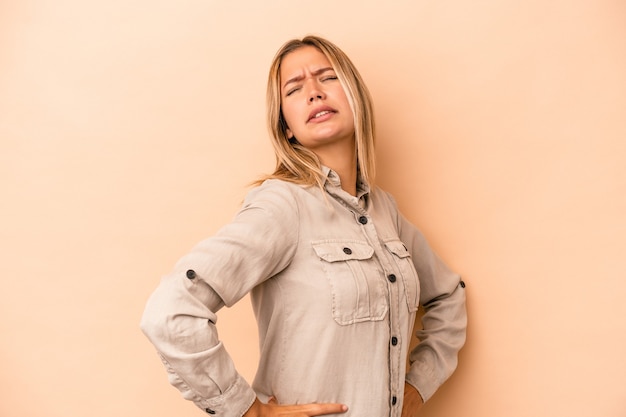 Young caucasian woman isolated on beige background suffering a back pain.