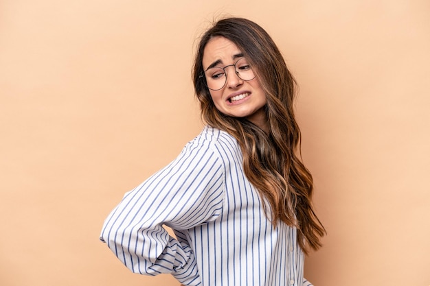 Young caucasian woman isolated on beige background suffering a back pain