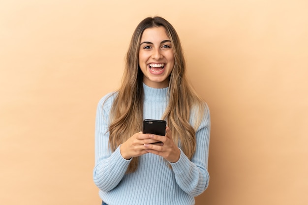 Young caucasian woman isolated on beige background surprised and sending a message